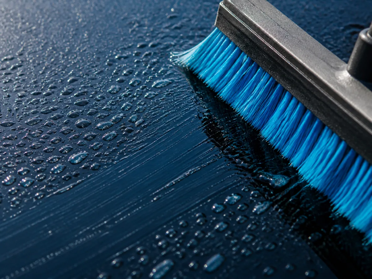 Close-up of a blue window-cleaning brush on wet glass